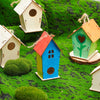 Colorful wooden bird houses of various sizes and colors placed in a green grassy landscape.