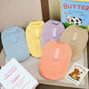 Colección de suéteres de invierno para perros de felpa cálida en varios colores pastel, dispuestos en una caja.