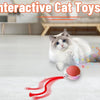 A white cat playing with an interactive ball toy that is red and features a USB charging cable.