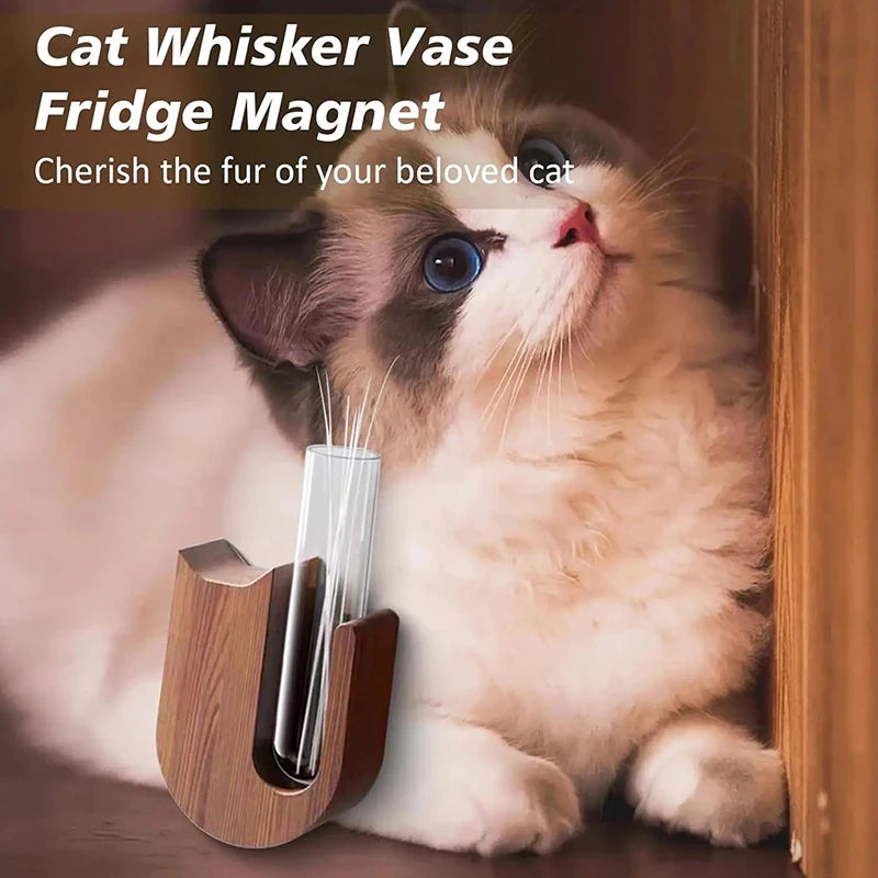 A fluffy white and gray kitten is looking up, with a wooden vase holding its whiskers, used as a fridge magnet.