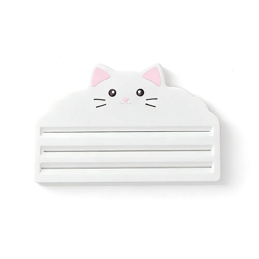 A white reusable cat food pouch scraper shaped like a cute cat face.