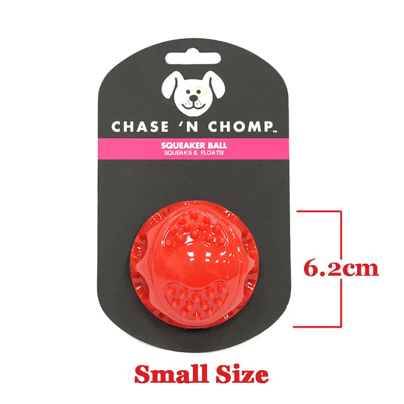 Un pequeño juguete para perros tipo pelota chirriante rojo con diseño de cara blanca en una etiqueta negra.