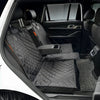 A black waterproof dog car seat cover with a safety strap installed in the back seat of a white vehicle.
