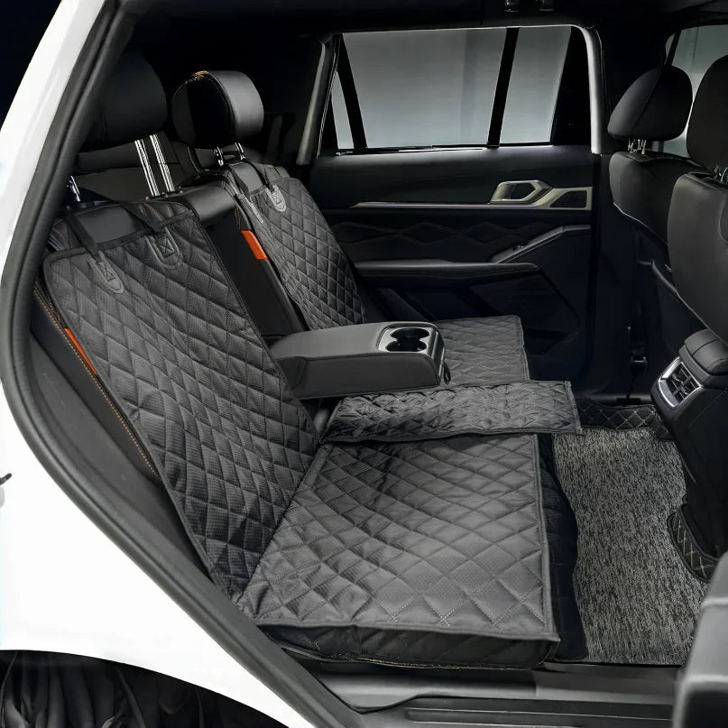 A black waterproof dog car seat cover with a safety strap installed in the back seat of a white vehicle.