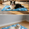 A blue pet mat with white octopus designs is placed on a wooden floor, featuring a calm cat.