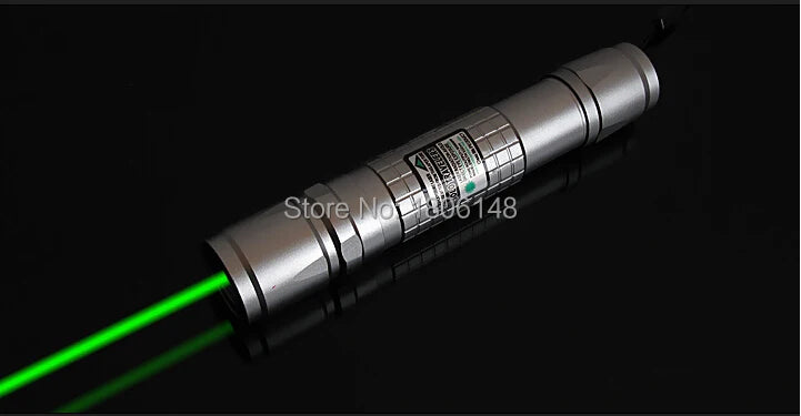 A silver laser pointer with a green beam shining across a dark surface.