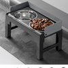 A black collapsible elevated dog feeder with two stainless steel bowls is shown on a floor.