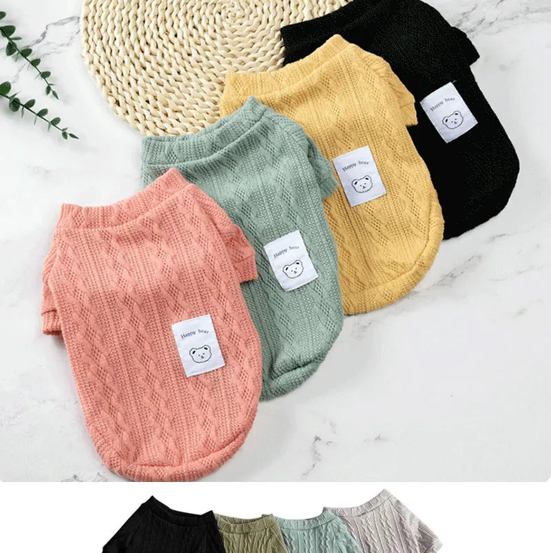 A collection of knitted winter sweaters for dogs and cats in various colors including beige, black, green, and pink.