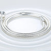 A silver snake chain necklace with a heart charm displayed on a white plate.