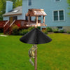 A wooden squirrel proof baffle guard with a roof structure and a squirrel perched on it, set in a grassy yard.