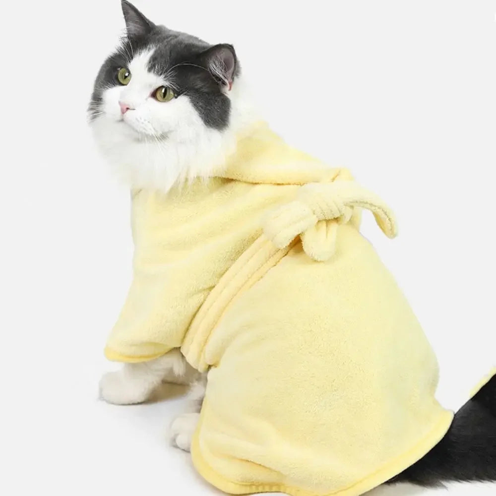 A fluffy gray and white cat wearing a yellow multi-purpose pet bath robe.