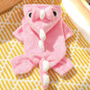 A pink fleece dog hoodie with animal ears lying on a yellow striped fabric.