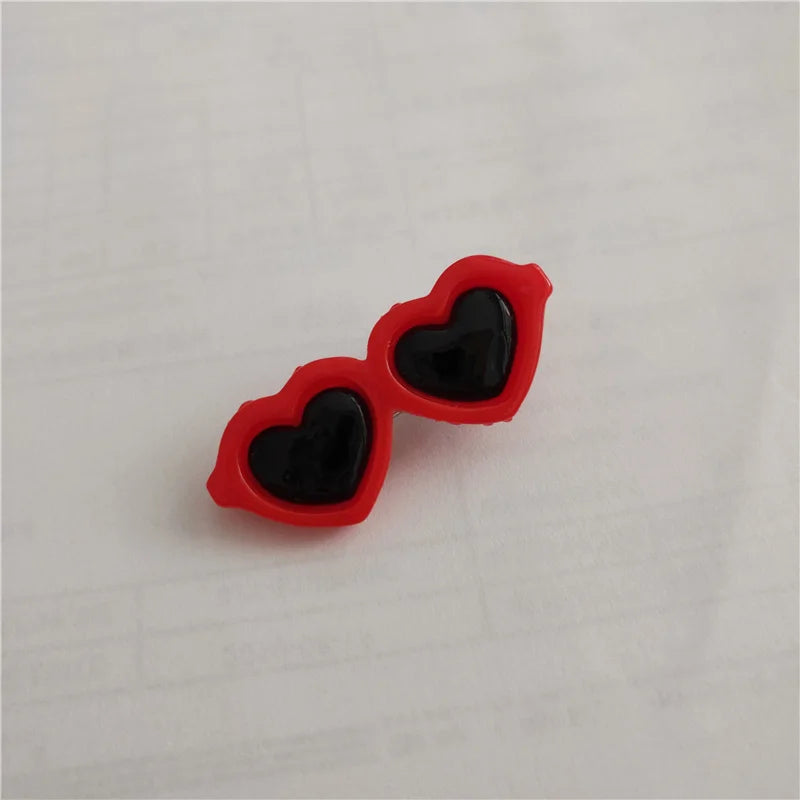 A pair of red heart-shaped pet hair clips with black centers resting on a white surface.