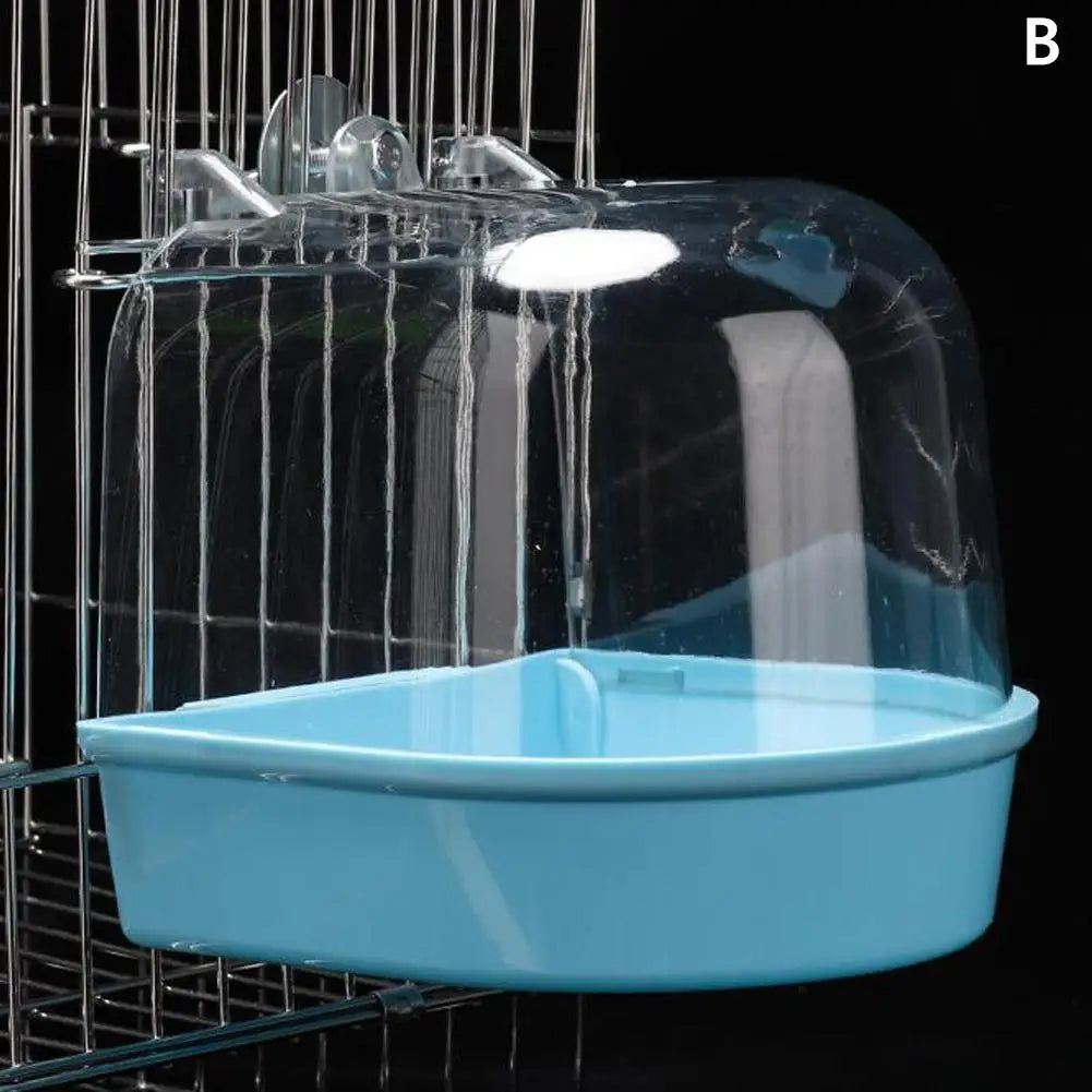 A clear plastic hanging bird bath for parakeets is suspended in a wire cage.