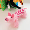 A pink plush toy shaped like a small dinosaur or pig is lying on a white surface.