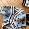 Suéter de perro tejido beige y azul con estampado de oso marrón.