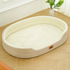 A beige washable waterproof dog bed mat with a shallow, oval shape is shown on a wooden floor.