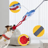 A dog is playing with a red tug-of-war rope toy featuring a shark head design.