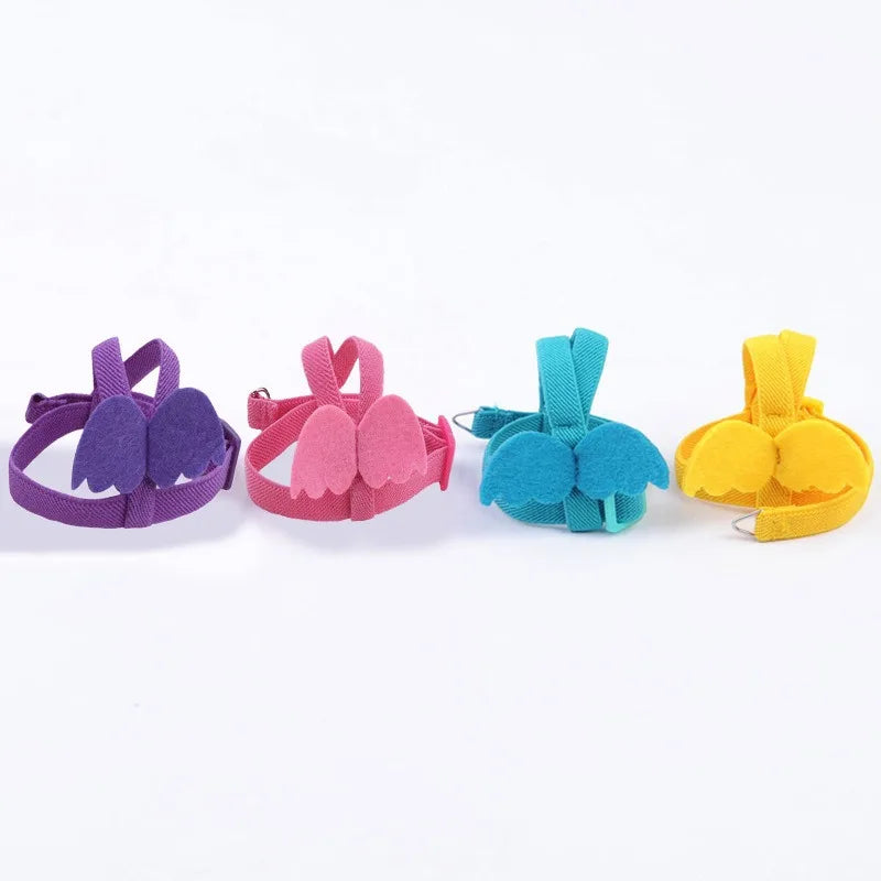 A set of four colorful parrot bird harnesses in purple, pink, teal, and yellow.