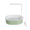 A white automatic bird bathtub with a clear resting stick and power cord.