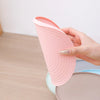 A hand holds a pink, wavy silicone pet feeding mat designed for dogs and cats.