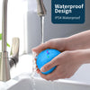 Eine Hand hält einen blauen elektronischen Haustierball, während Wasser aus einem Wasserhahn in die Spüle fließt.