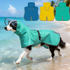 A black and white dog is running in shallow water wearing a teal raincoat, with color options displayed above.