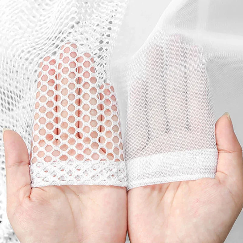Una mano sostiene una bolsa de ropa y accesorios de malla blanca reutilizable.
