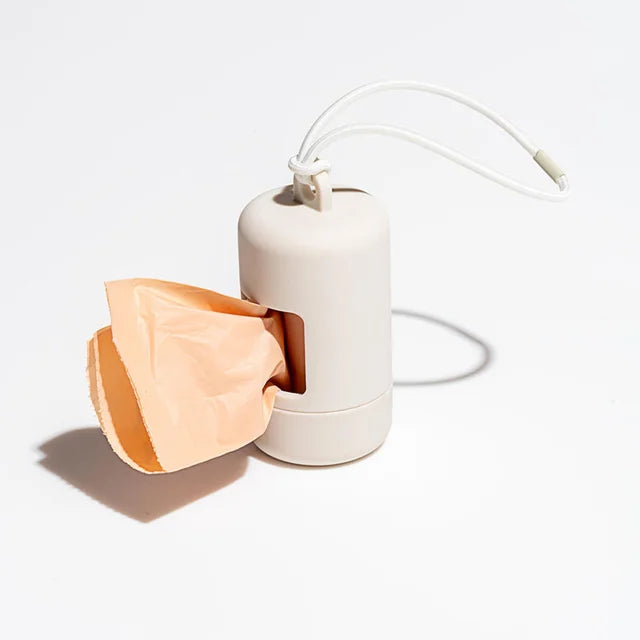 A white portable dog poop bag dispenser with a flexible bag and a white strap is shown against a light background.