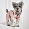 A fluffy gray dog wearing a pink waterproof reflective raincoat and jumpsuit.