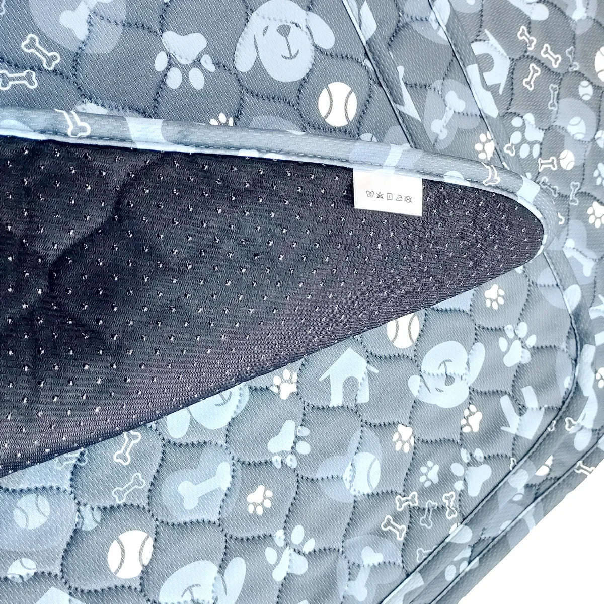 A close-up view of a gray and white patterned reusable absorbent dog pee pad with a dark gray quilted insert.