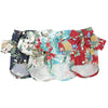 A flat lay of a set of Hawaiian leaf print dog shirts in various floral patterns.