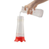 Una mano vierte líquido en un comedero de plástico transparente que contiene líquido rojo para atraer hormigas o abejas.