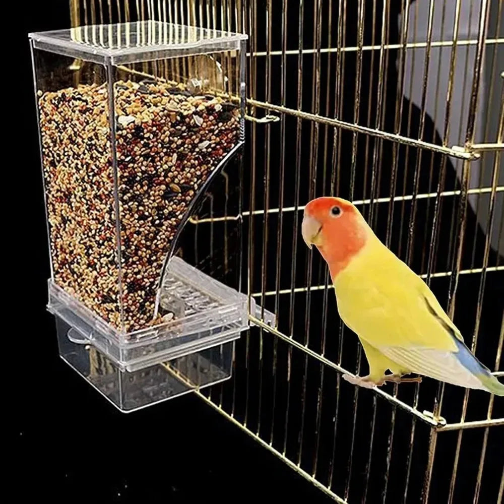 Un distributeur d'oiseaux en plastique transparent rempli de graines est placé dans une cage de fil avec un perroquet jaune e