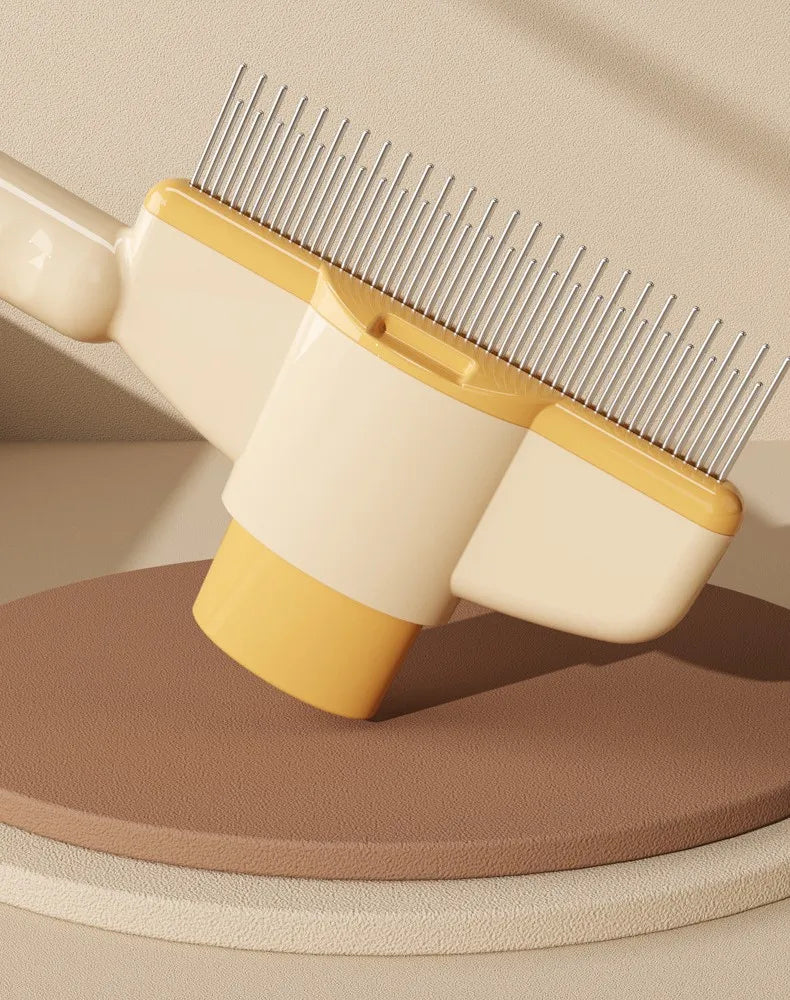 A close-up view of a yellow and white self-cleaning pet brush with massage pins resting on a wooden surface.