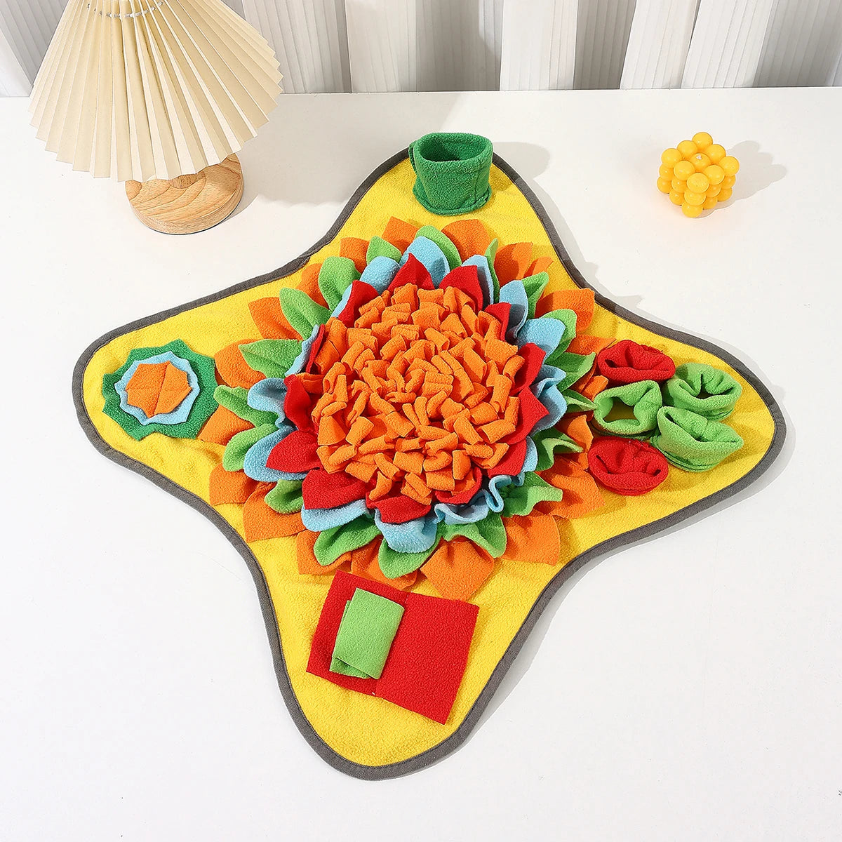A colorful, textured snuffle mat for dogs featuring various fabric pieces and a puzzle element.
