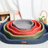 A stack of colorful washable waterproof dog bed mats in shades of blue, green, and orange resting on a white surface.