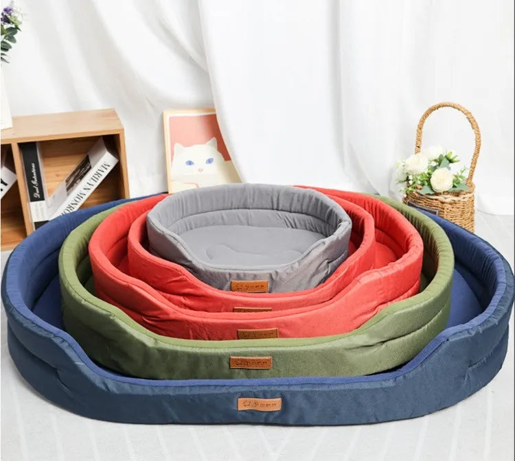 A stack of colorful washable waterproof dog bed mats in shades of blue, green, and orange resting on a white surface.