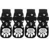 A set of four black anti-slip dog socks with traction straps featuring white paw prints.