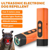 An orange ultrasonic electronic dog repellent device with a black body and a dog looking at it.