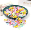A pile of colorful bone-shaped hair clips for pet grooming, featuring pink, yellow, purple, and green hues.