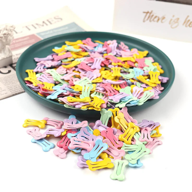 A pile of colorful bone-shaped hair clips for pet grooming, featuring pink, yellow, purple, and green hues.