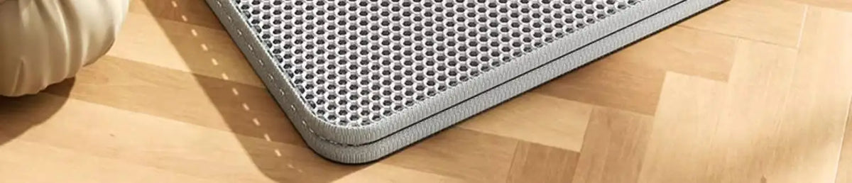 Graue, strapazierfähige, wasserdichte Katzenstreumatte auf einem hellen Holzfußboden.