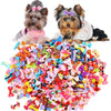 A dog and a cat sitting next to a large pile of colorful handmade bows for pets