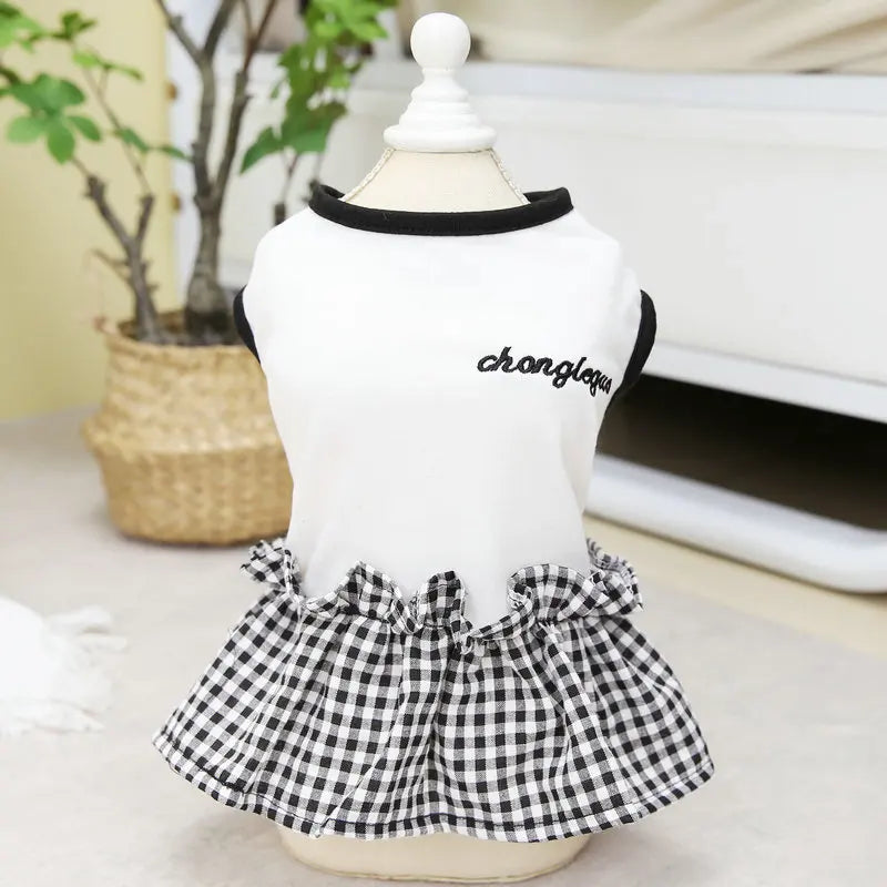 A white short-sleeved top with a black collar and a black and white checkered skirt displayed on a mannequin.