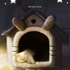 A fluffy white kitten is resting inside a cozy, house-shaped pet bed for indoor use.