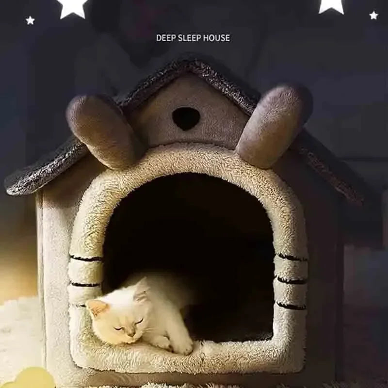 A fluffy white kitten is resting inside a cozy, house-shaped pet bed for indoor use.
