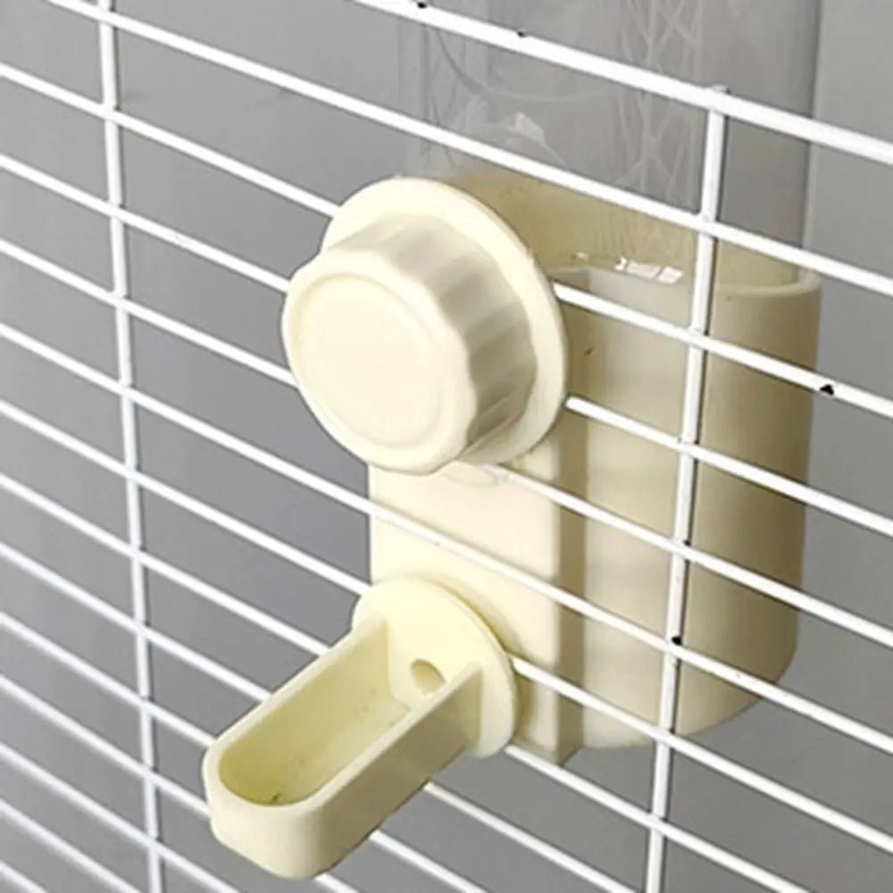 Beige wiederverwendbarer Vogel-Wasserfutter mit rotierender Ausgabestation und Futteröffnung, montiert auf einem Drahtgitter.