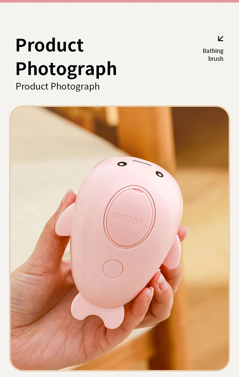 A hand holds a pink Petspa electric pet grooming brush with a steam comb in a natural indoor setting.
