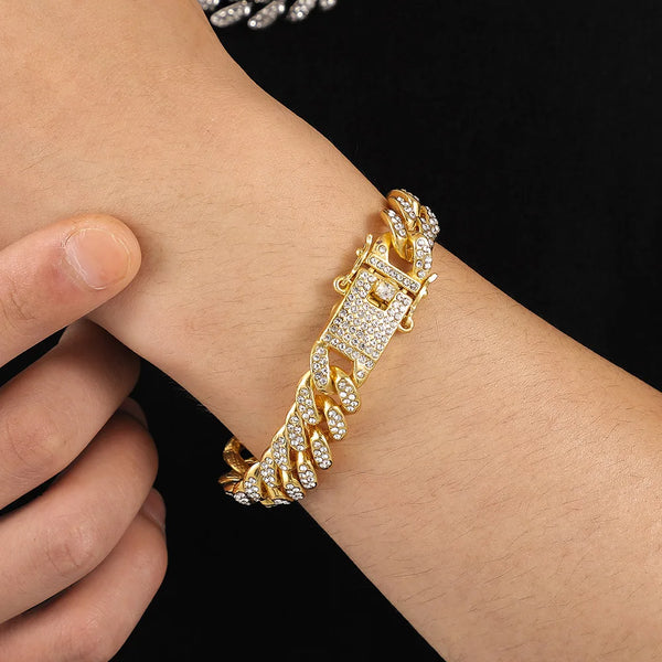 A close-up of a gold Cuban link chain bracelet with rhinestone accents worn on a wrist.